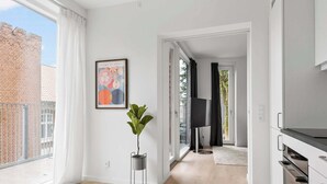 Eine moderne Wohnung mit großem Fenster, einem Blumentopf, einem gerahmten Kunstwerk und einer Küchenzeile.