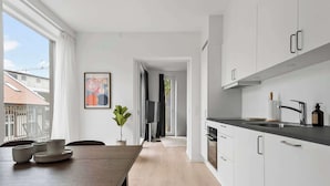 Eine moderne Küche mit weißen Schränken, einer dunklen Arbeitsplatte und Blick ins Freie.