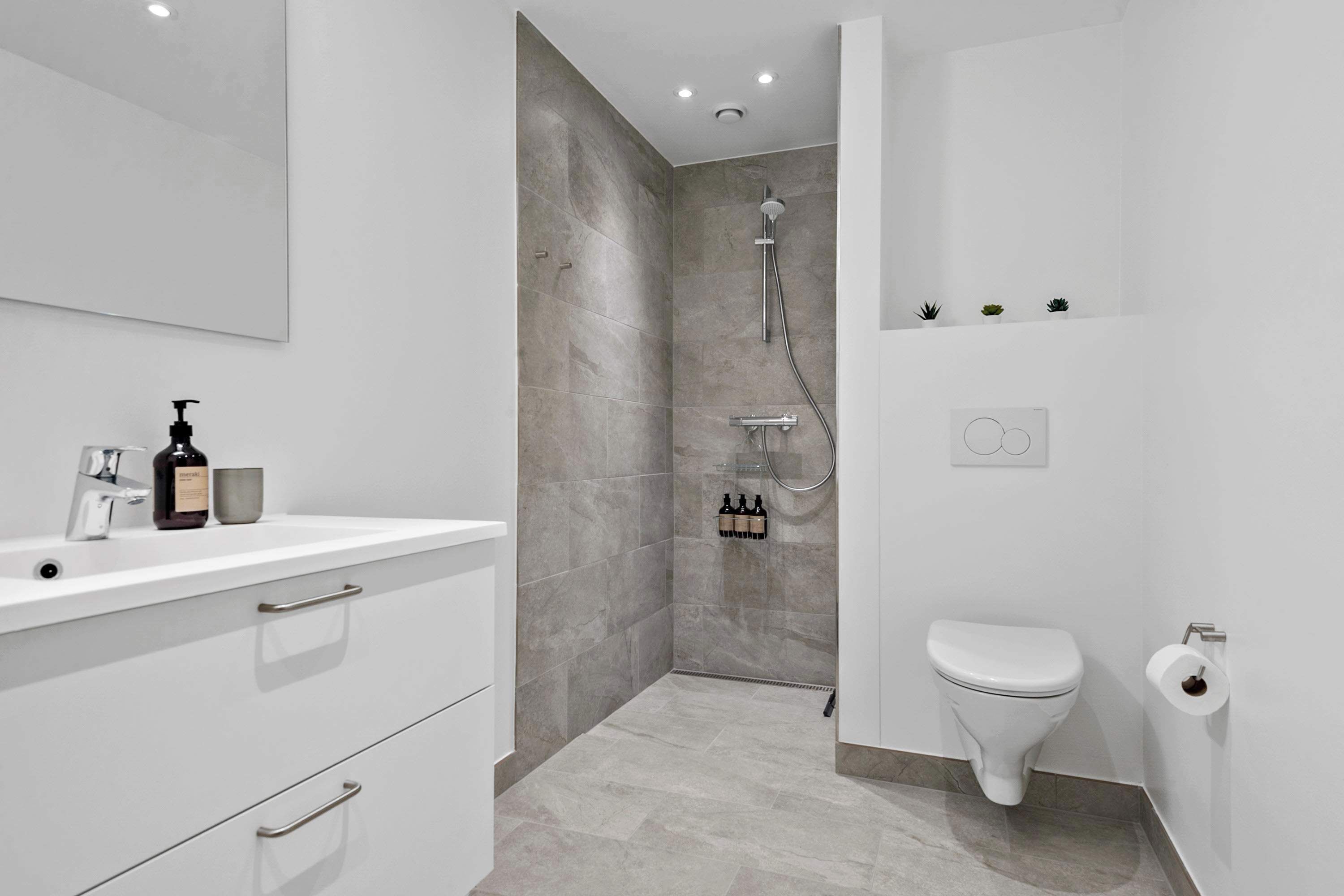 A modern bathroom with a shower, toilet, and vanity.