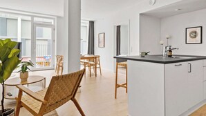 Une cuisine moderne avec des armoires blanches, un comptoir noir et un évier. On y trouve également un coin repas avec des chaises et une table en bois.