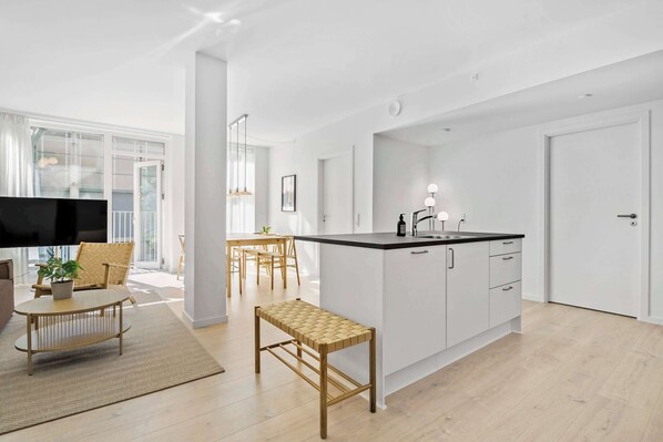 A modern kitchen with white cabinets, a black countertop, and a built-in sink.