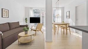 Un salon moderne comprenant un canapé, une table basse ronde, un téléviseur et un coin repas avec une table et des chaises.