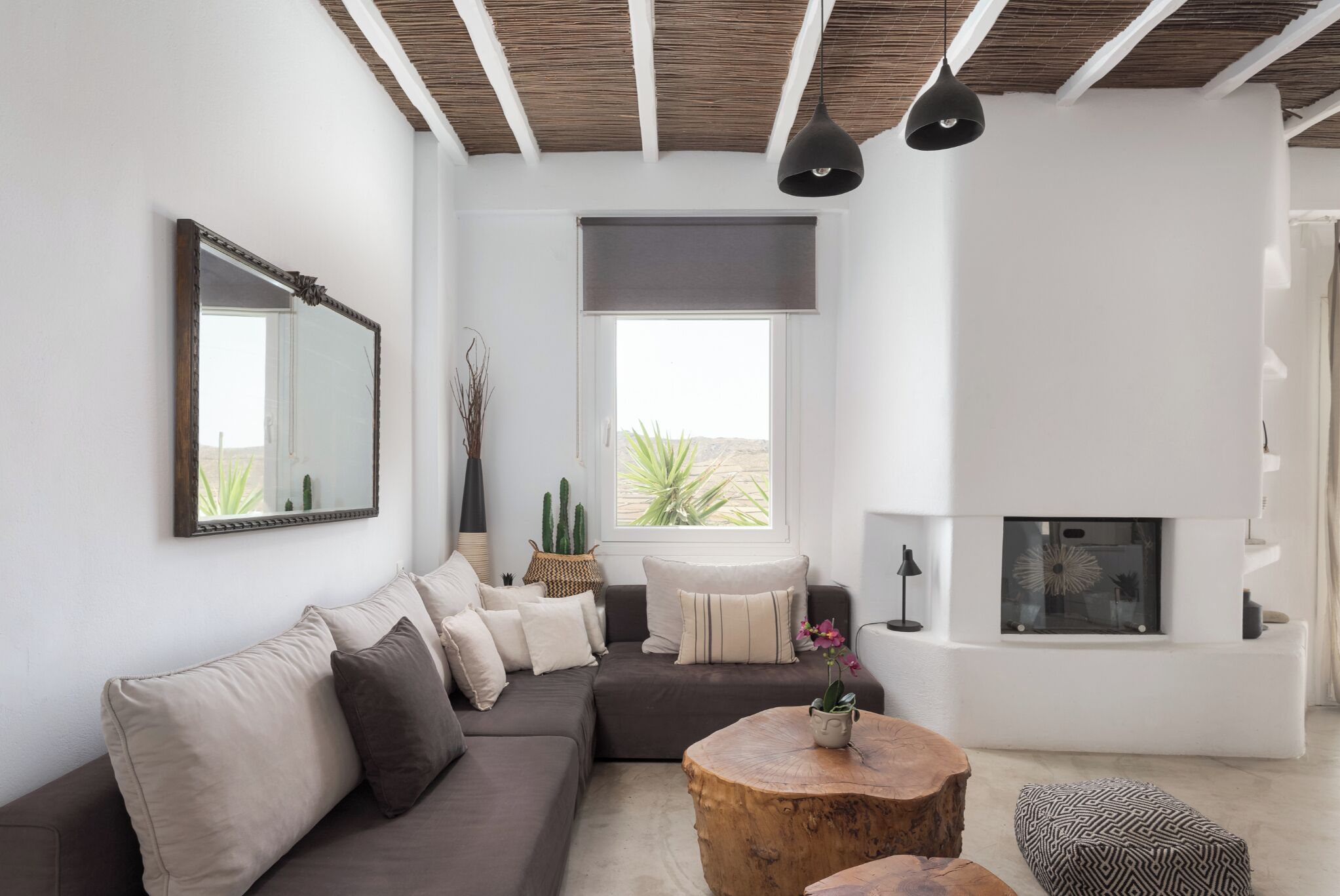 Ein modernes Wohnzimmer mit einer Eckcouch, einem runden Couchtisch aus Holz, einem Kamin und einem großen Fenster mit Blick.