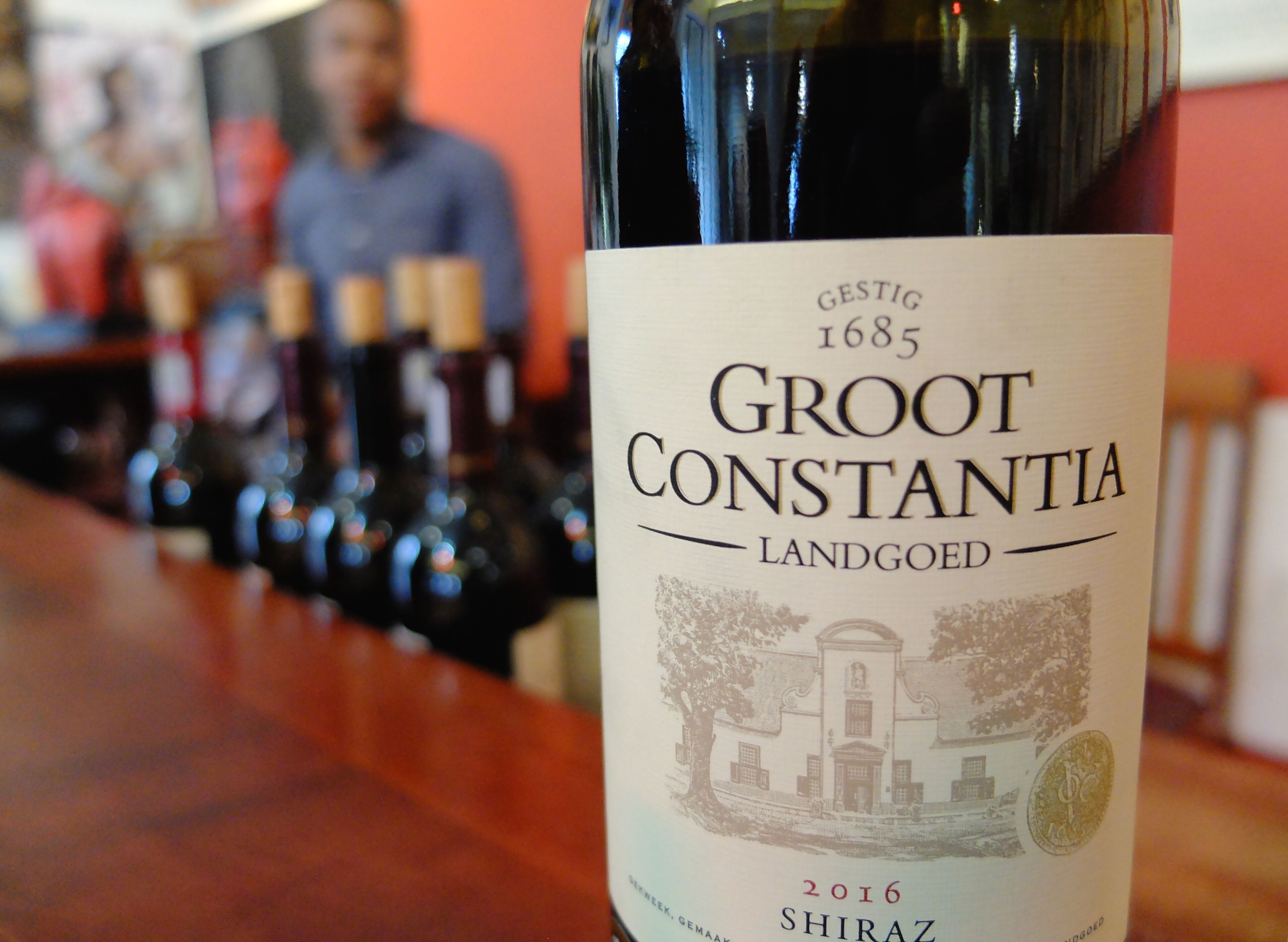 A bottle of Groot Constantinia wine with a label indicating it is a 2016 Shiraz.