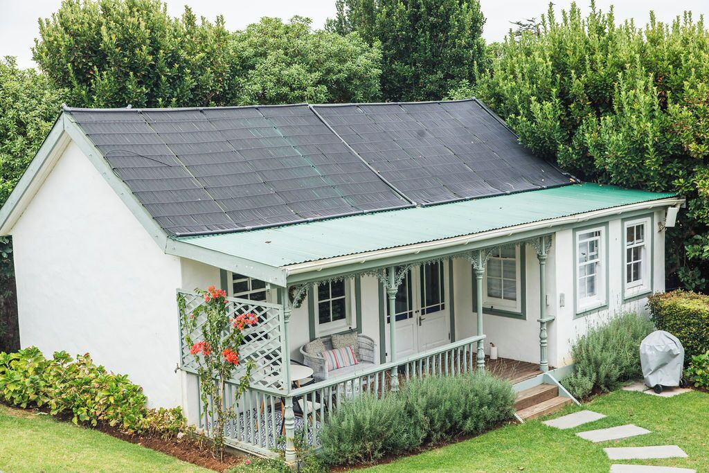 Een huis met een groen dak, een overdekte veranda en een tuin.