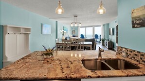 Une cuisine dotée de plans de travail en granit, d’un évier double, d’un éclairage suspendu et donnant sur l’espace repas.