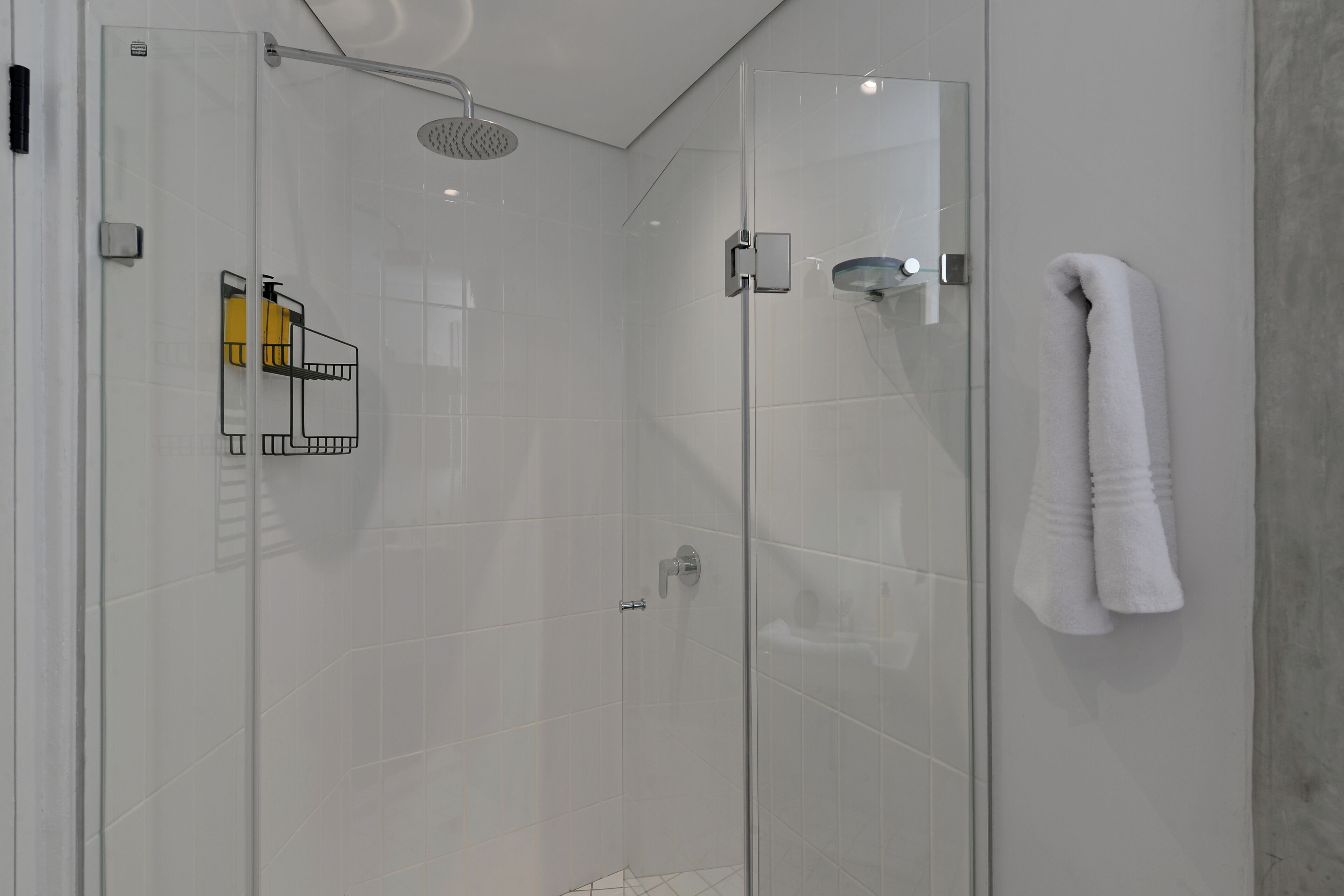 Un baño moderno con ducha de vidrio, un perchero y una puerta de vidrio para la ducha.