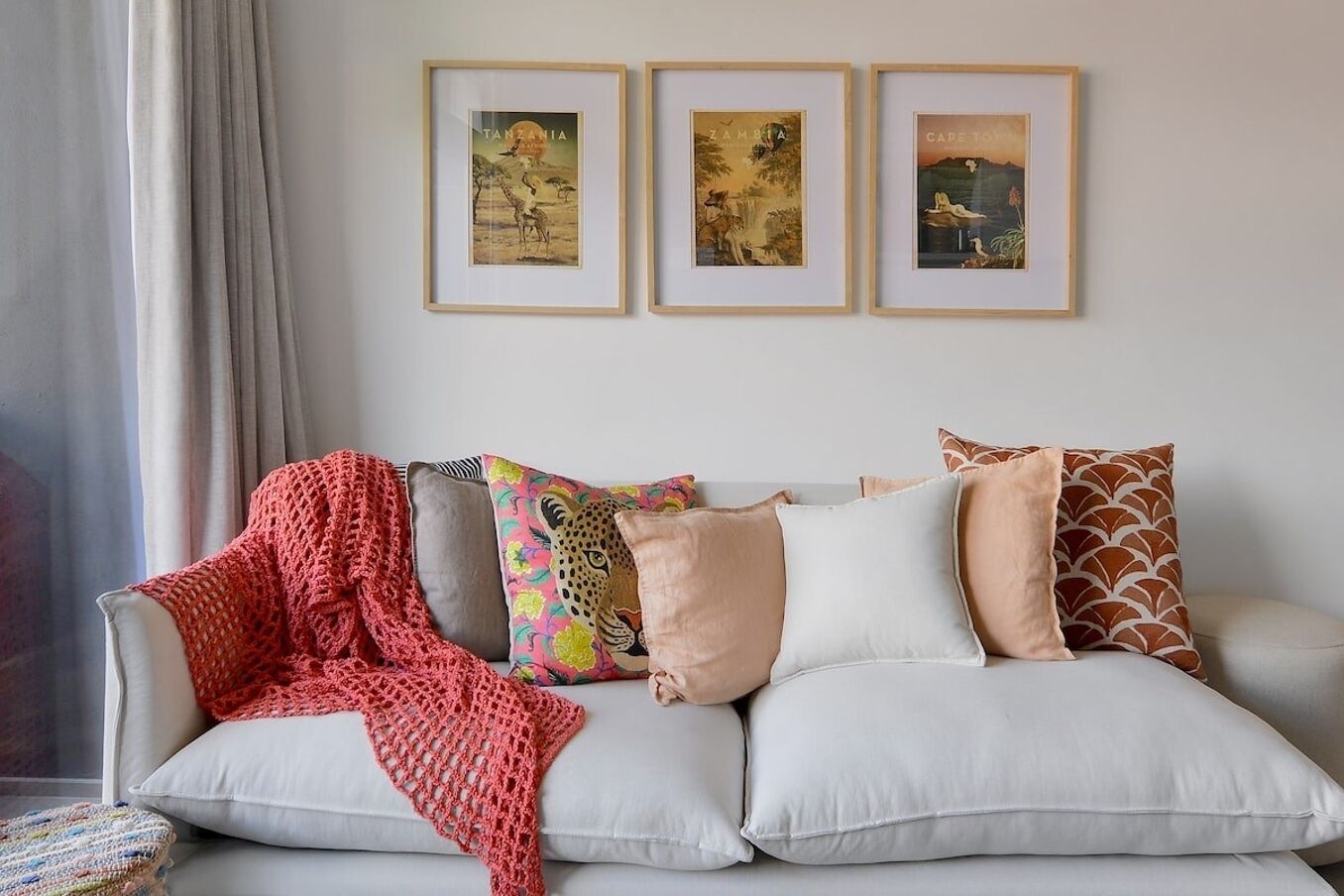 A living room with a sofa, a red knitted blanket, and three framed pictures on the wall.