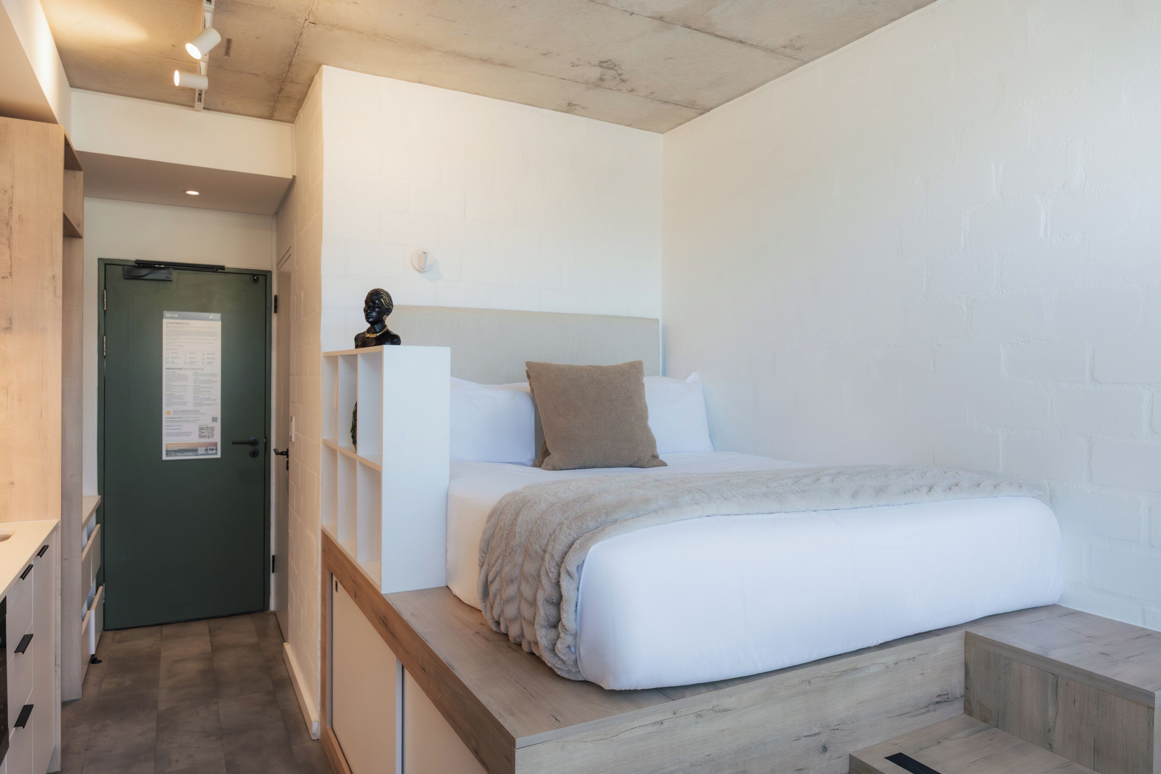 Un dormitorio con cama, mesita de noche y una puerta con un aviso.