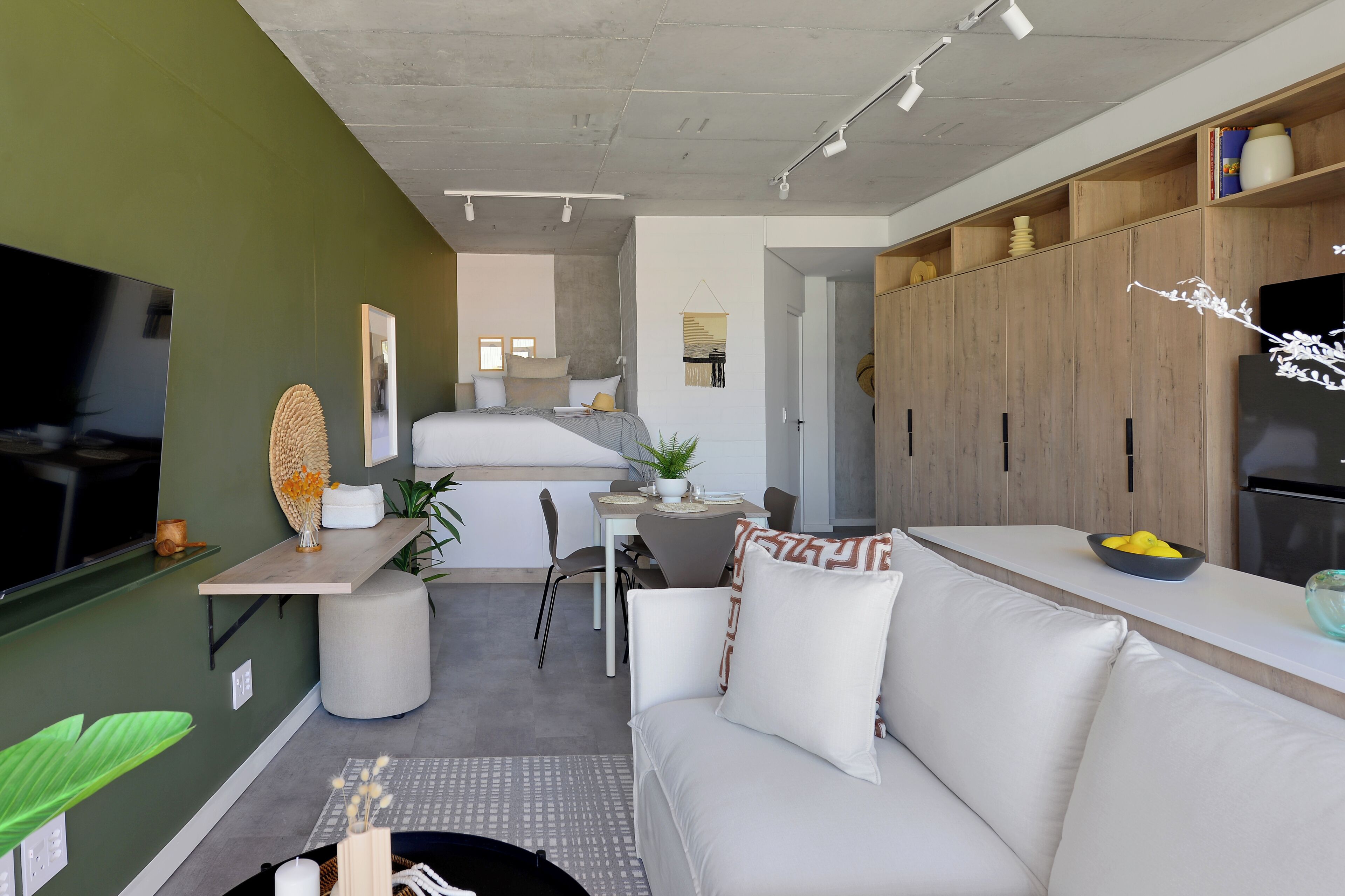 A modern living room with a sofa, a dining area, and a kitchen.