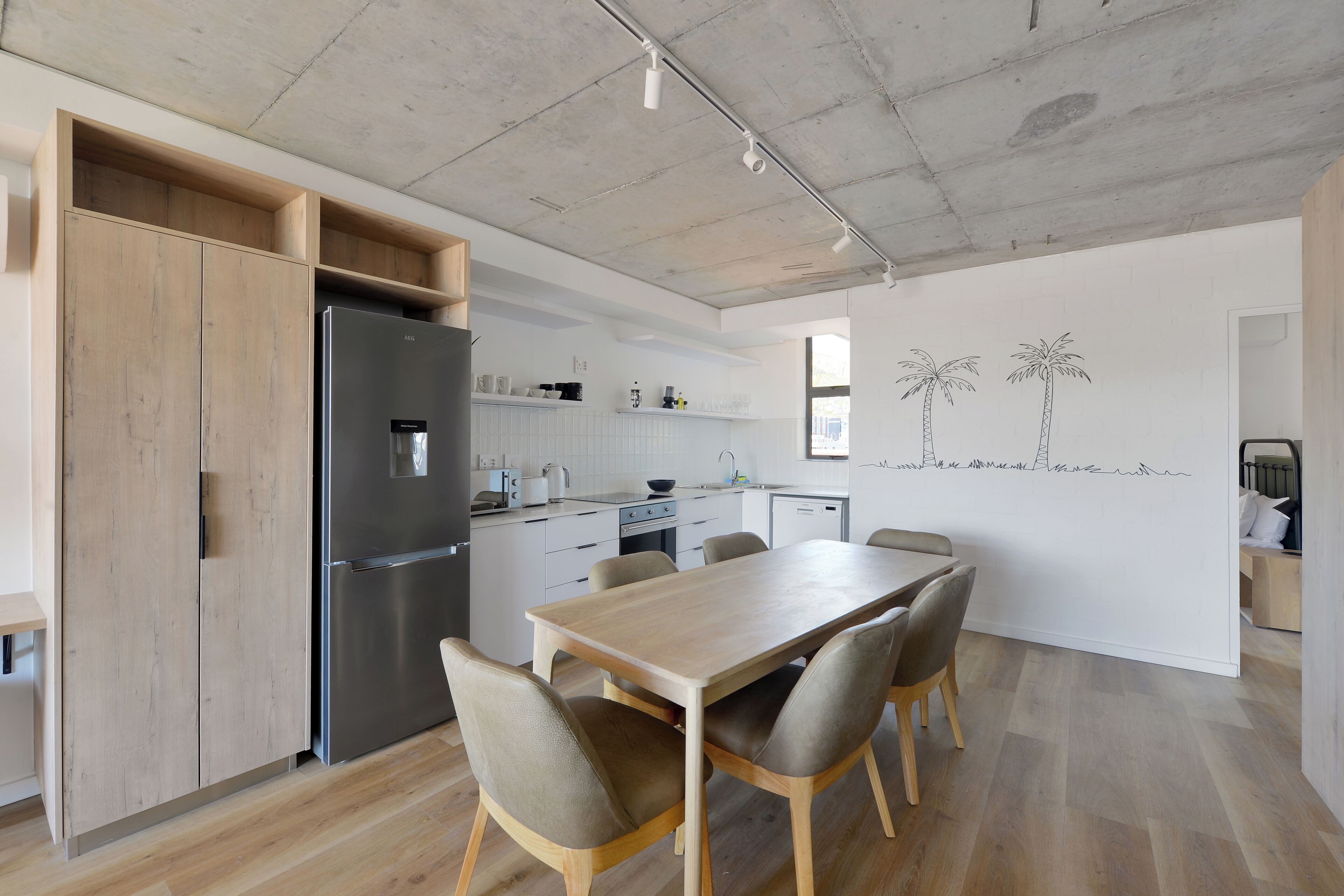 A modern kitchen with a large island, built-in appliances, and a dining area with a wooden table and chairs.