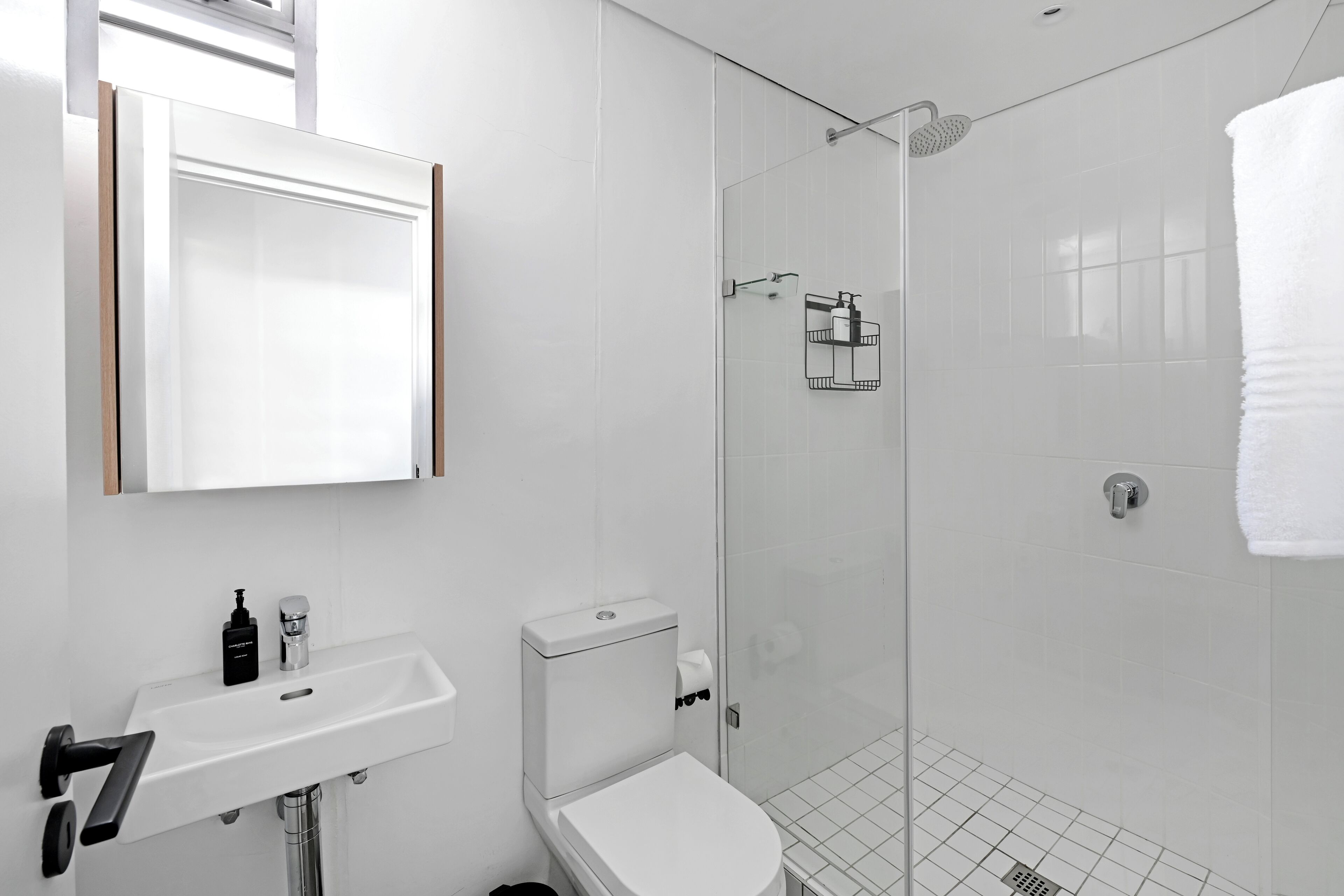 Ein modernes Badezimmer mit Waschbecken, Toilette und Dusche in Weiß.