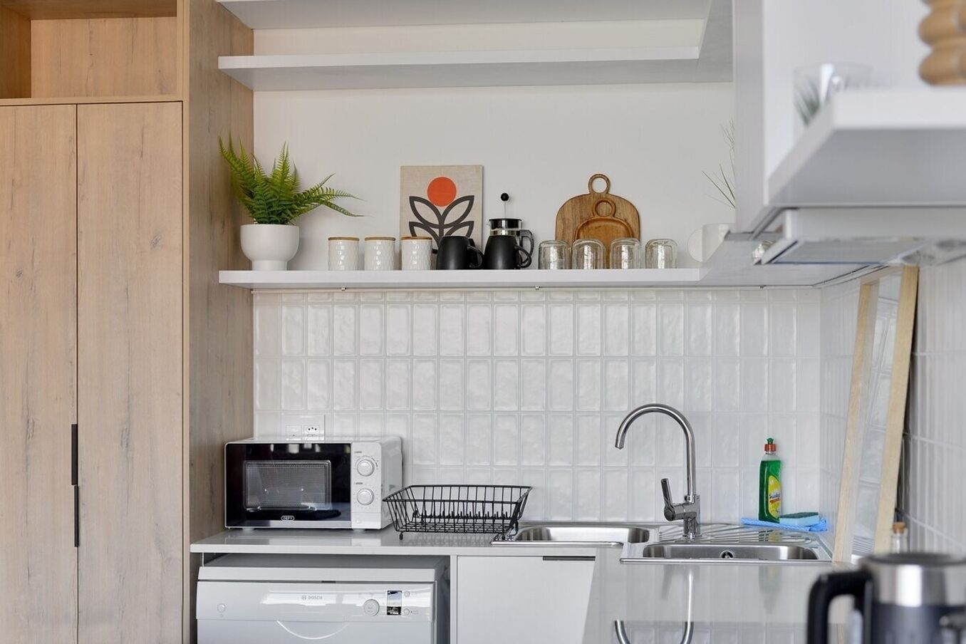 Una cocina compacta equipada con microondas, tostadora, lavabo y lavavajillas Bosch.