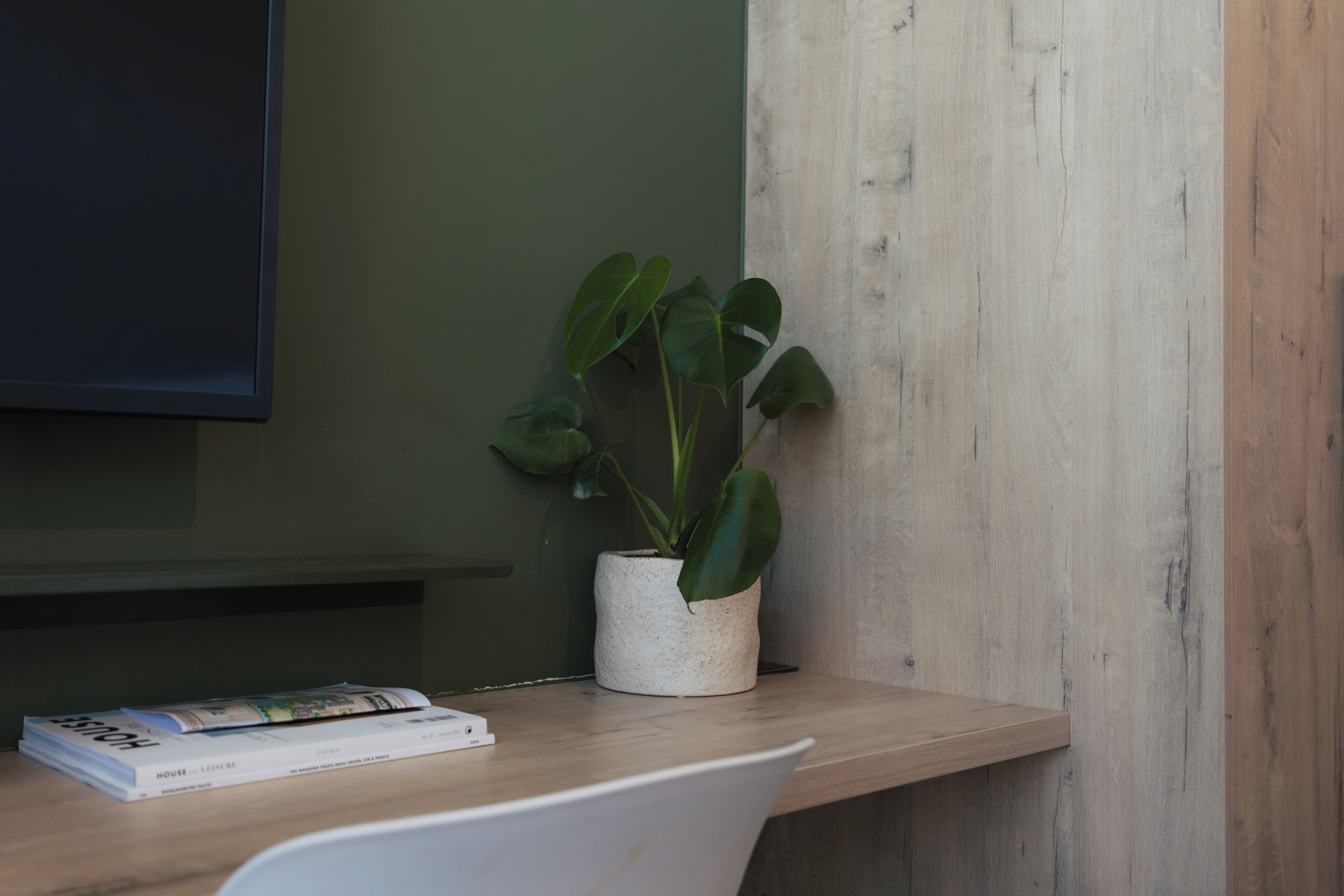 Un bureau en bois, avec une plante en pot et un livre.