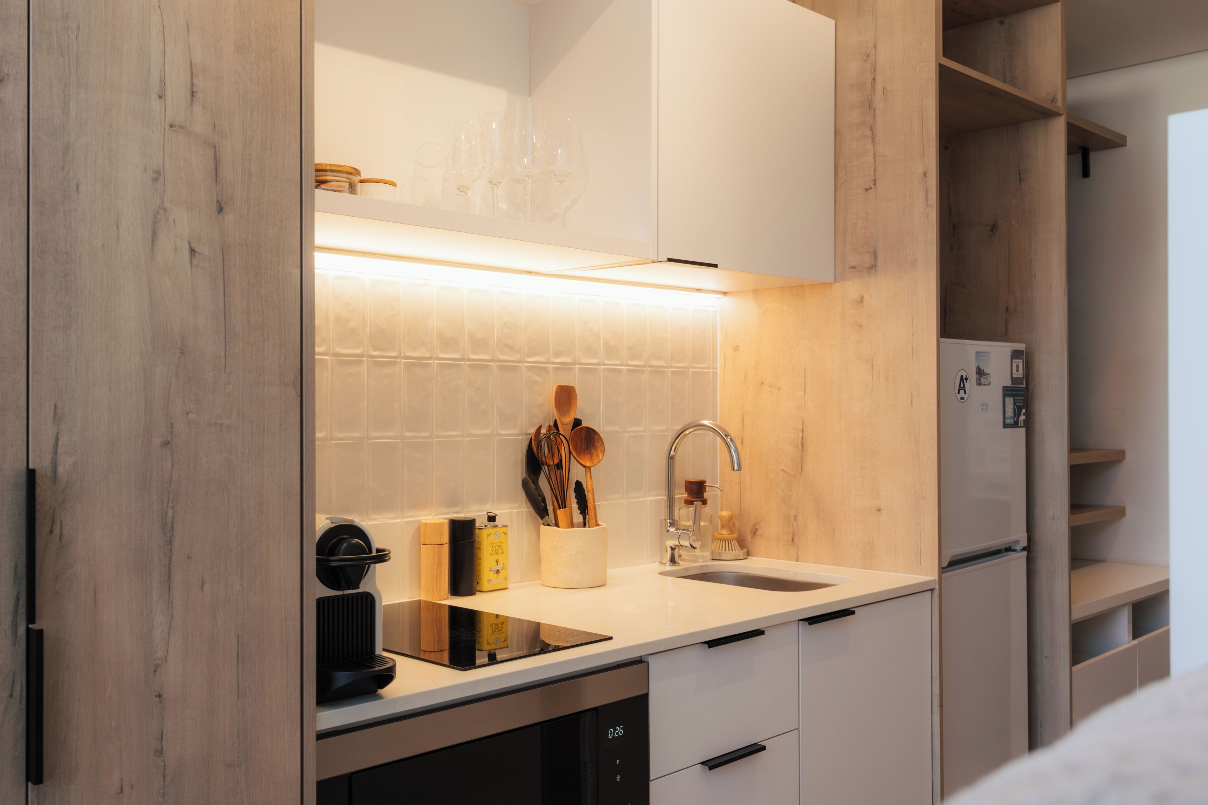 A modern kitchen with a built-in dishwasher, a stainless steel sink, and wooden cabinets.