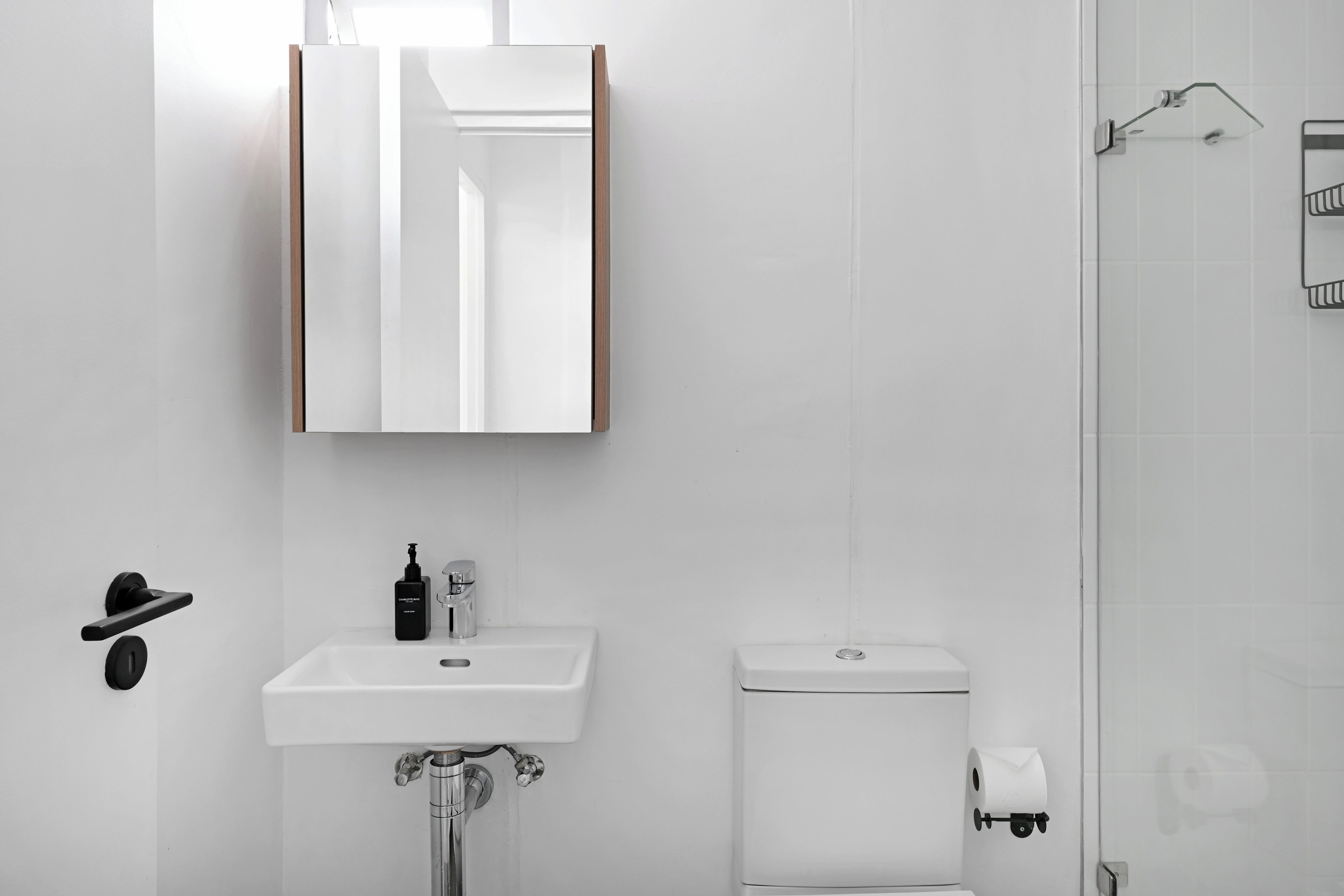 Une salle de bain moderne avec un lavabo blanc, un miroir et des toilettes.