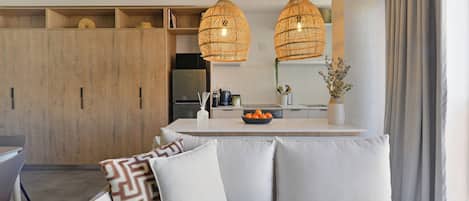 Une cuisine moderne avec des meubles en bois, un réfrigérateur encastré et un îlot central agrémenté d’un panier de fruits.