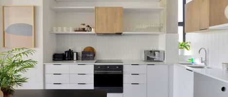 A modern kitchen with white cabinetry, a black oven, and a wooden cabinet above the stove.