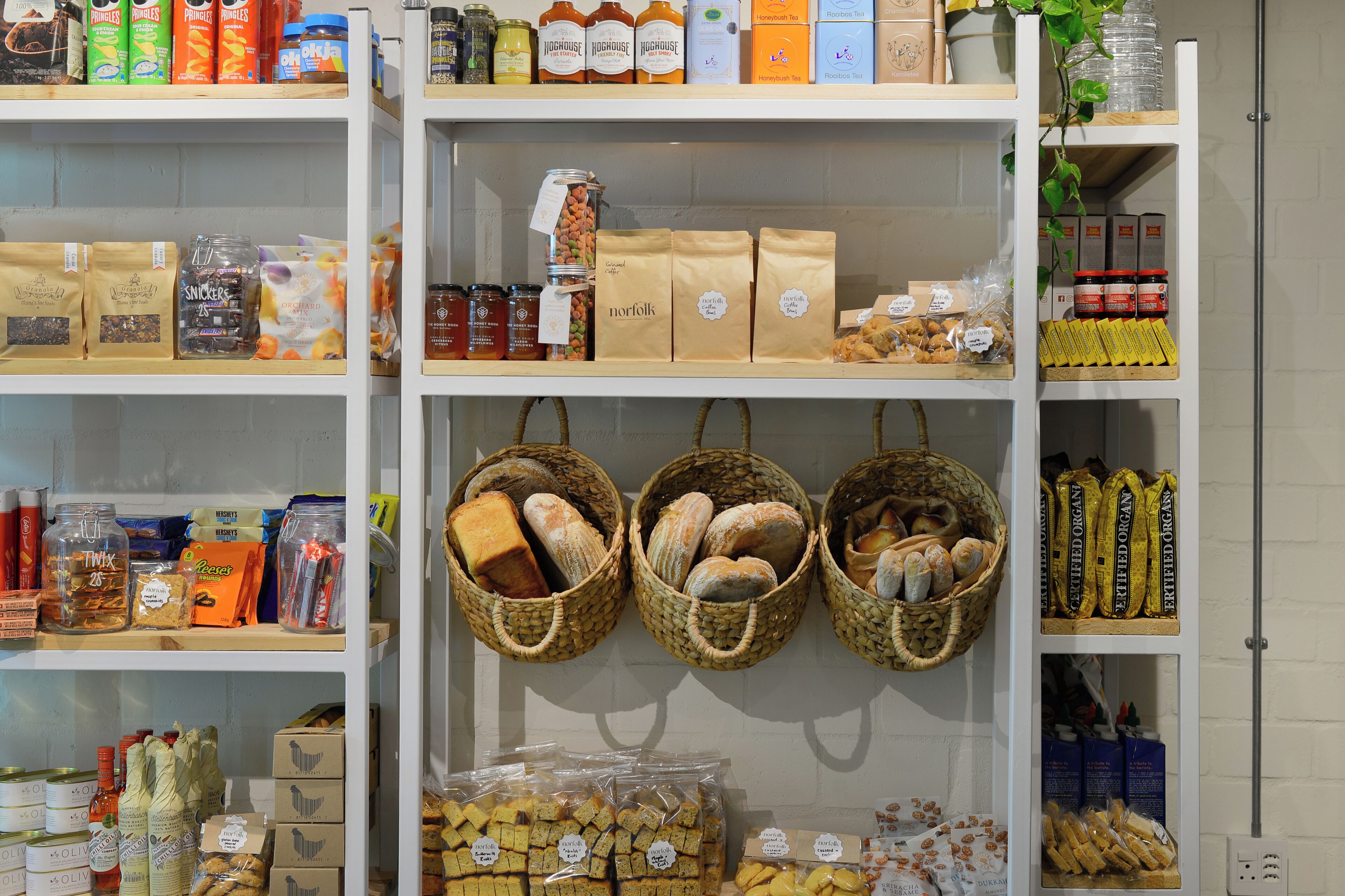 Variedad de productos envasados en estantes, como aperitivos, bebidas y alimentos.