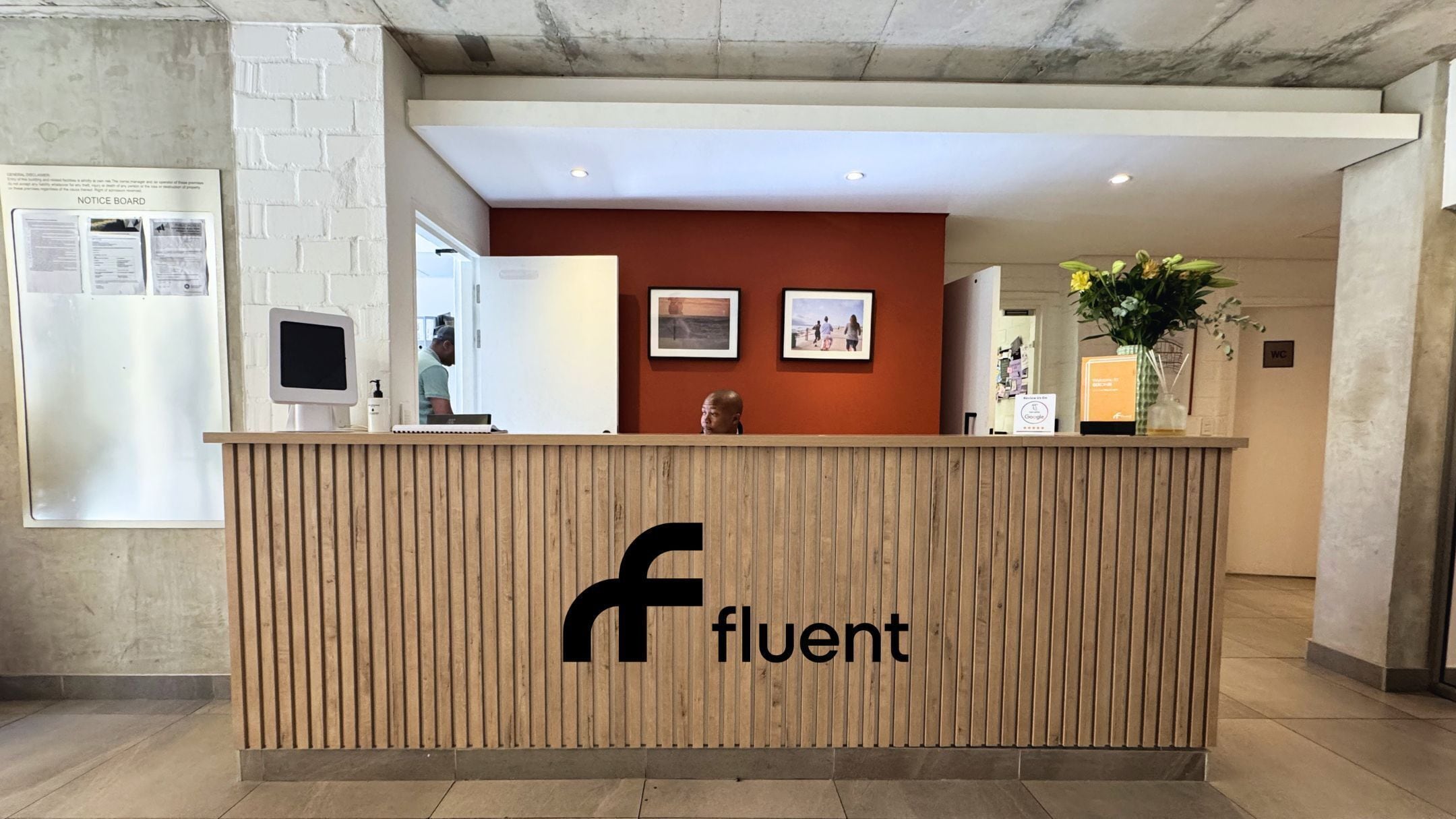 Ein Empfangsschalter mit Holzausstattung, einem Logo und einem digitalen Bildschirm.
