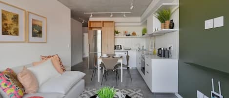 A modern living room with a sofa, coffee table, and a dining area with chairs.