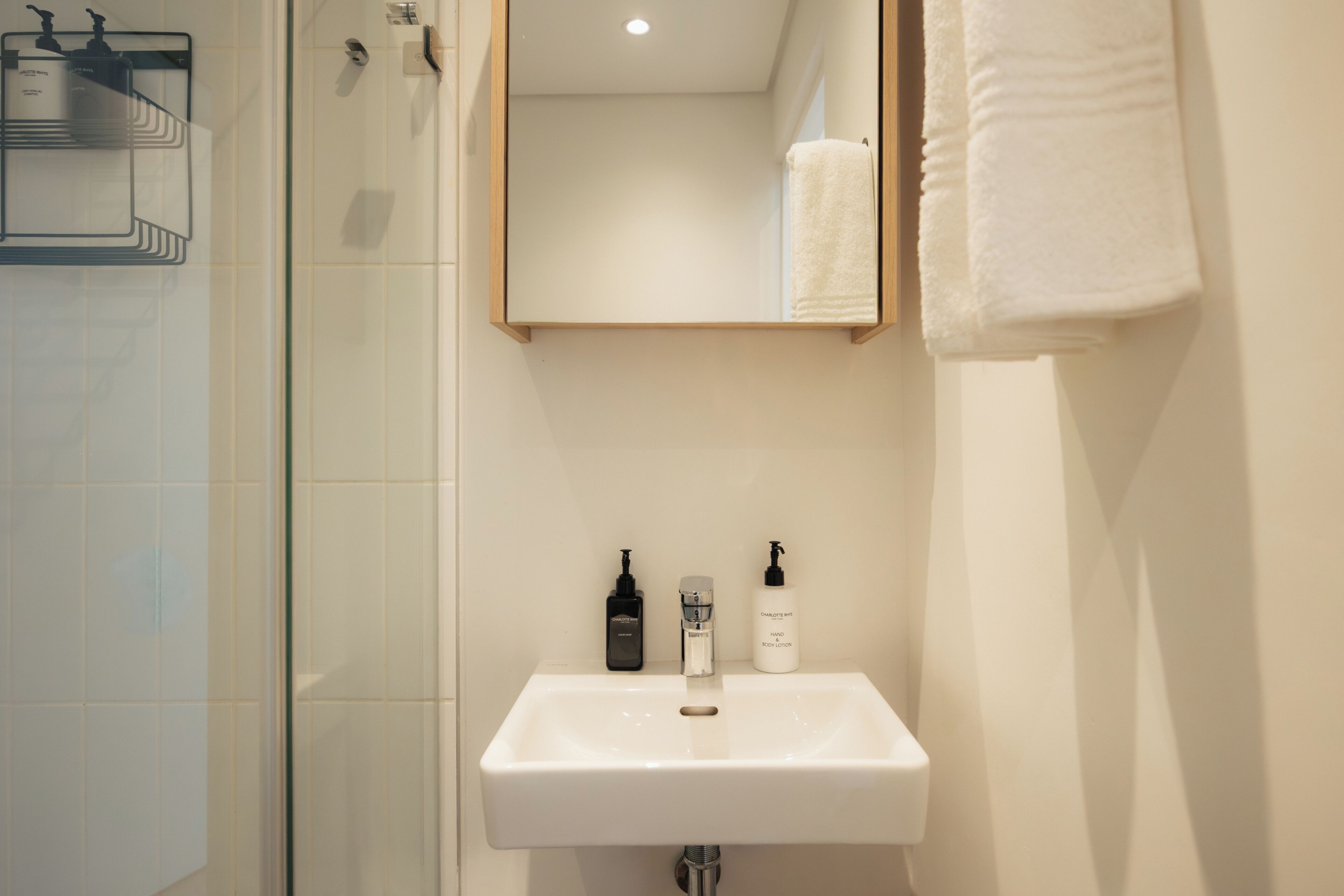 A bathroom with a white sink, a mirror, and two bottles of lotion.