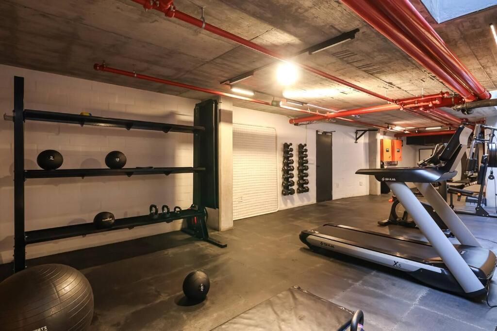 Ett gym med träningsutrustning, ett löpband och en väggmonterad knäböjsställning.