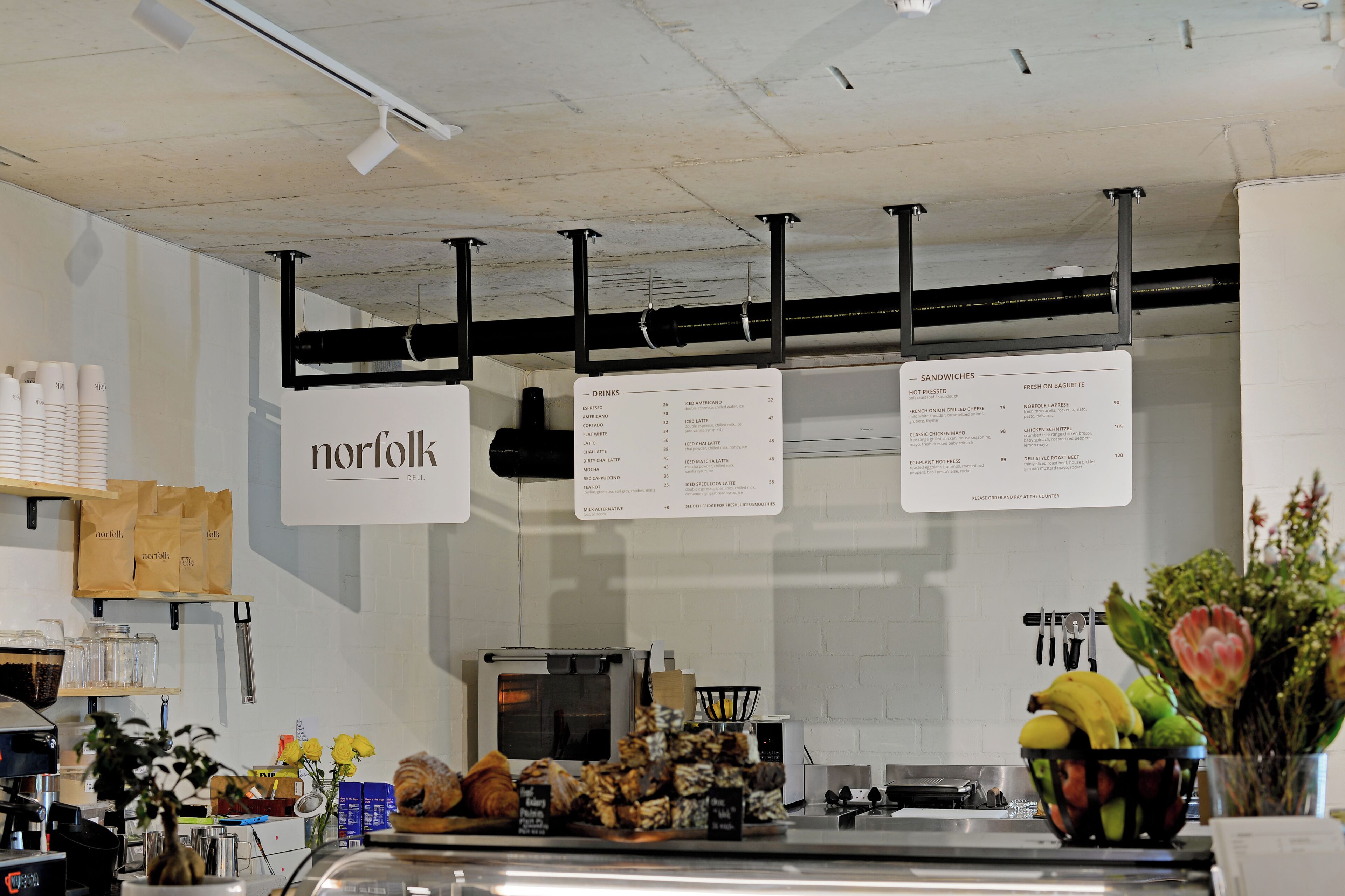 A deli counter with a menu board displaying various food and drink options.