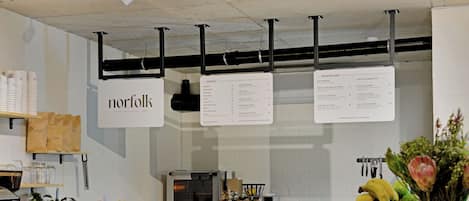 A deli counter with a menu board displaying various food and drink options.