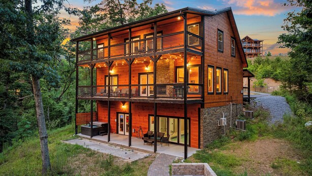 A two-story log cabin with a balcony, outdoor seating, and a fire pit. - New Listing! Indoor pool, hot tub, theater, bocce, billiards, & firepit. (Sevierville)
