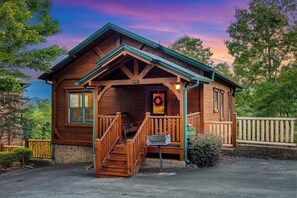 A wooden cabin with a porch, a mailbox, and a stone wall.