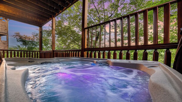 Ein Whirlpool mit einer Holzterrasse und Geländer, umgeben von Bäumen.