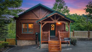 Eine Blockhütte mit Veranda, einer Haustür mit Weihnachtskranz und einem Steinfundament.