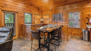 Ein Holzblockbau-Innenraum mit Esstisch, Stühlen und Kamin.