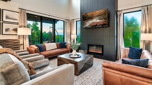 A modern living room with leather sofas, a coffee table, and a fireplace. - Brand New Modern Luxe 6 Bed w/ Arcade Games, Indoor Pool, Great Views! (Sevierville)