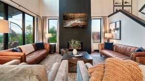 A modern living room with leather sofas, a coffee table, and a fireplace. - Brand New Modern Luxe 6 Bed w/ Arcade Games, Indoor Pool, Great Views! (Sevierville)