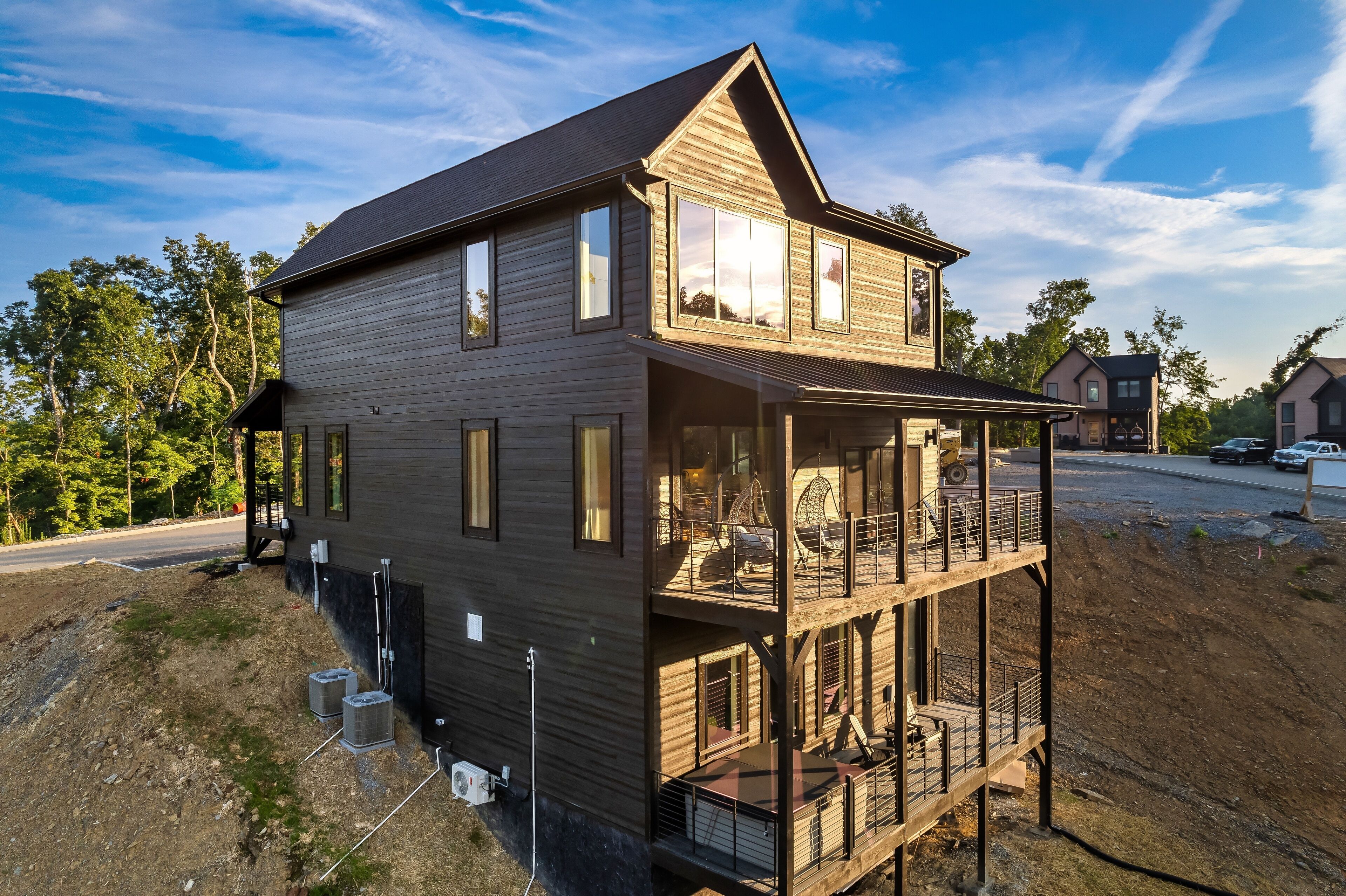 Una casa a due piani in legno con un balcone, ampie finestre e un cantiere edile in vista.