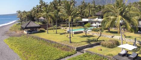 A resort with a pool, lounge chairs, and a beach view.