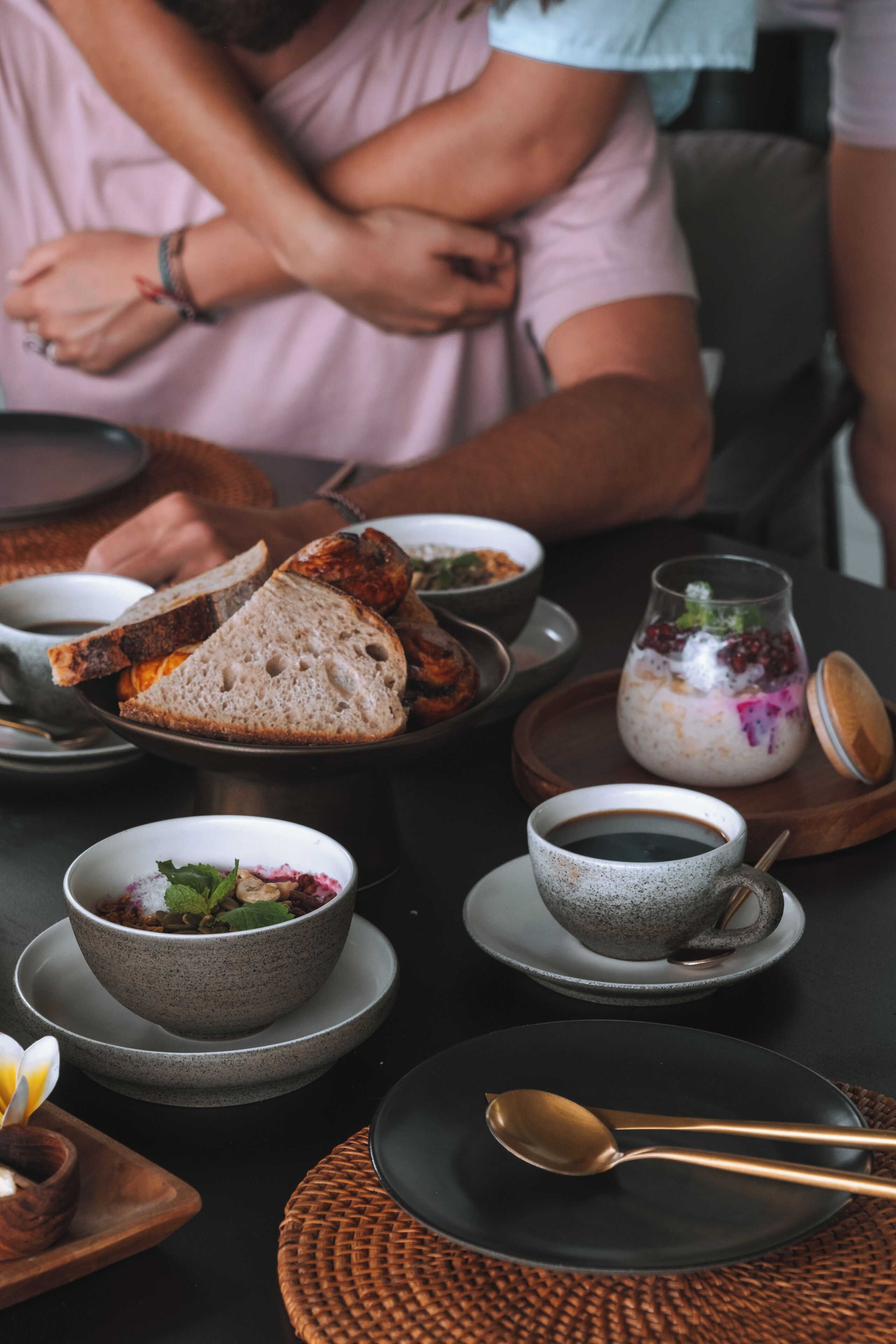 Uma mesa de jantar com diversos pratos, incluindo pão, tigelas e um pote com tampa.