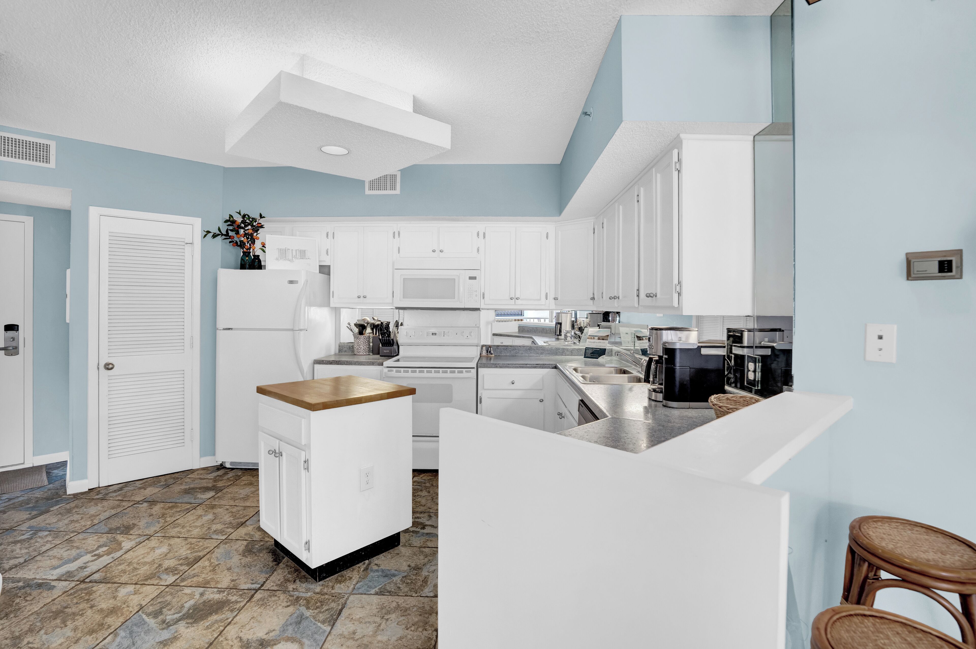 Una cocina moderna con armarios blancos, una isla central y un microondas integrado.