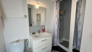 A bathroom with a toilet, sink, mirror, and shower. - Cozy Avignon Apartment Intra muros  (Avignon)