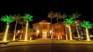 A hotel entrance with palm trees, a dome-shaped building, and a sign that reads 'OFFICE.'