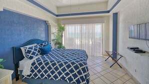 A bedroom with a bed, curtains, a ceiling fan, and a TV.
