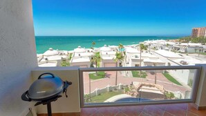 A balcony with a view of the ocean and resort buildings.