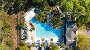 An aerial view of a resort with a swimming pool, lounge chairs, and a fenced area. - Golf Cart+4 Bikes! 5 Min to the Pool, 10 to Beach! 2 King Suites & Custom Bunks! ~ Baha Beach House at WaterSound West on 30A (Santa Rosa Beach)