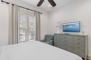 A bedroom with a bed, a dresser, a chair, a television, and a window with blinds.