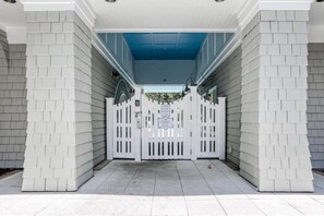 Une entrée fermée par un portail, avec un plafond bleu et des murs blancs.