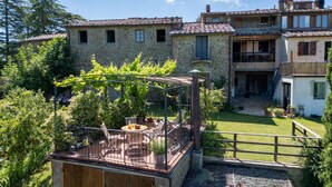Ein Steinhaus mit überdachter Außenbestuhlung und einem Garten.