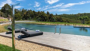 Une terrasse en bois avec des chaises longues et une piscine.