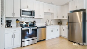 A modern kitchen with white cabinets, stainless steel appliances, and a dishwasher. - MLK #104 xxxxxxxxxxx (Austin)